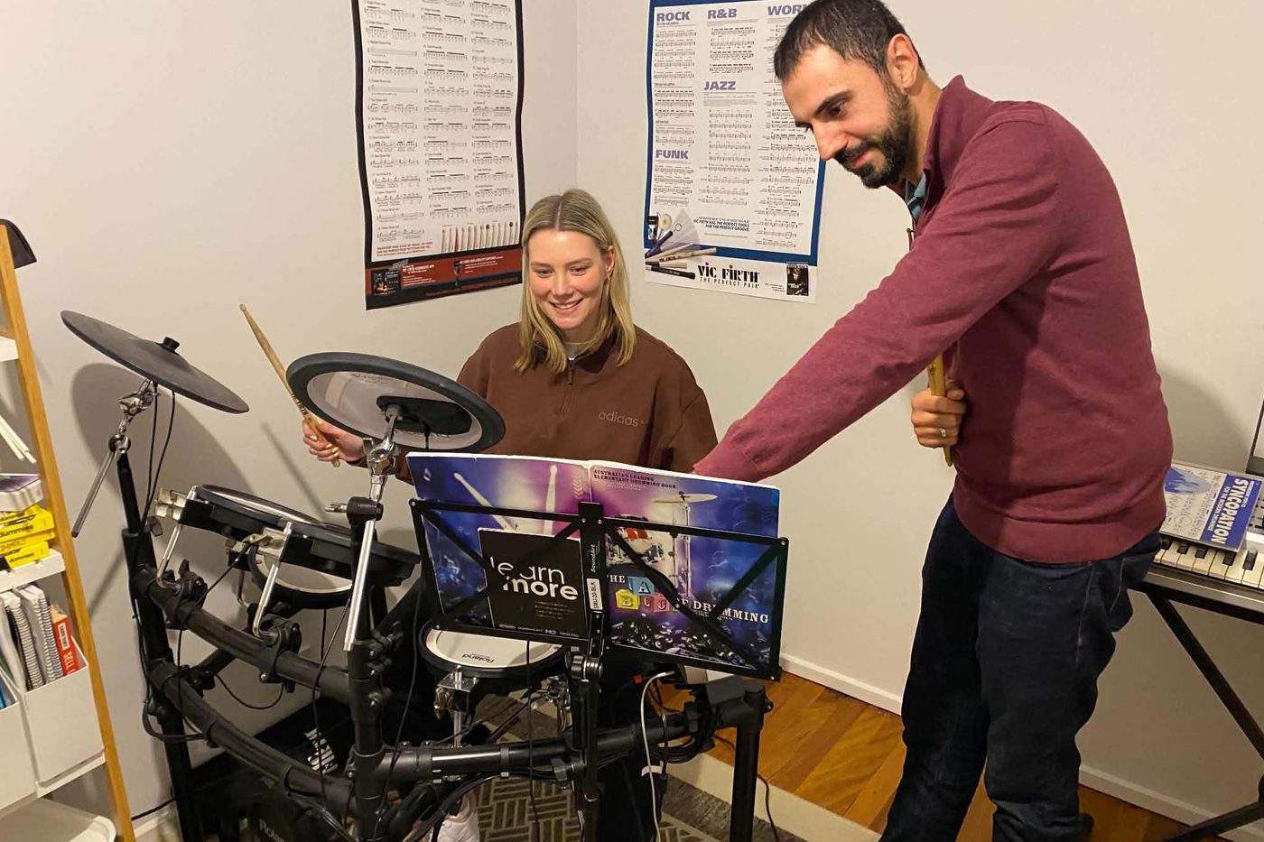 Peter teaching a student at the electronic drum kit, with rudiments and groove charts on the wall