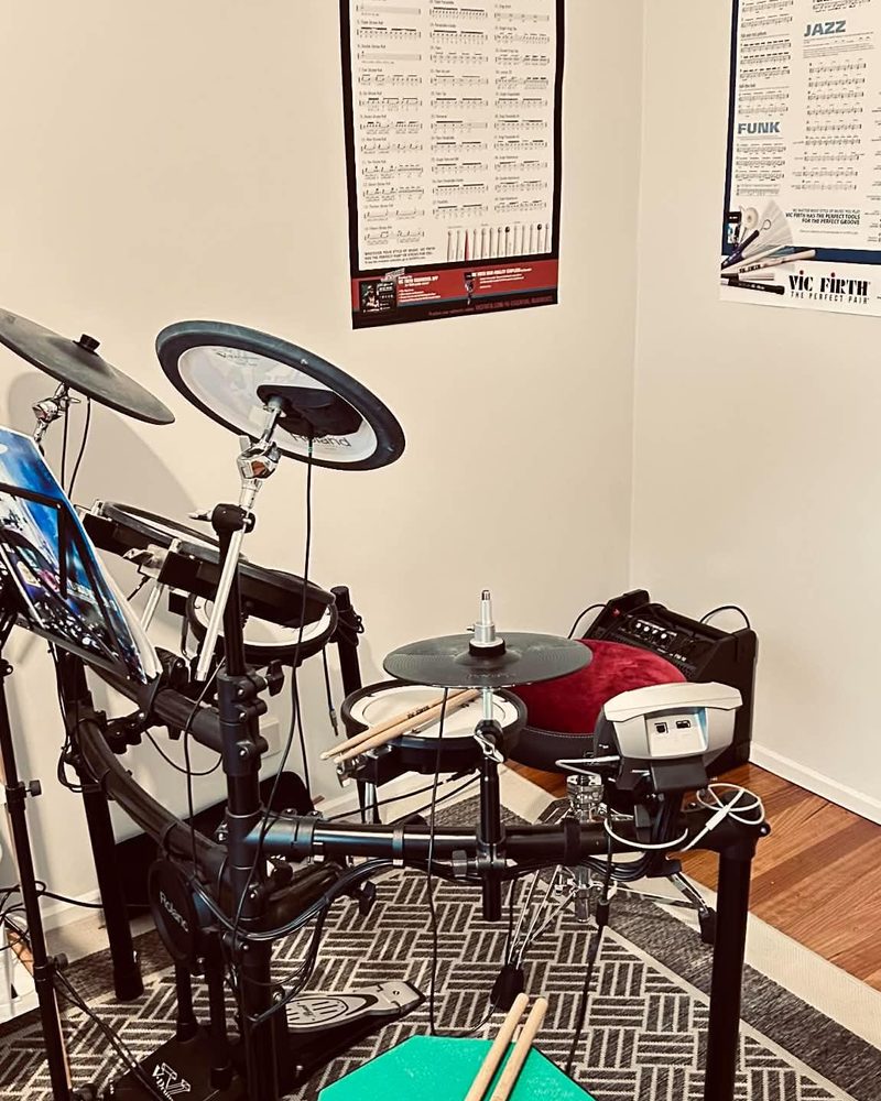 The Roland electronic drum kit set up beneath Vic Firth rudiments and Groove Essentials posters